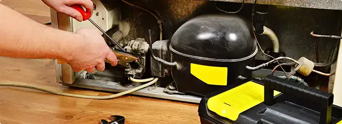 Refrigerator repair technician fixing the compressor and wiring in Upper Darby, PA