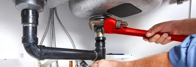 Garbage disposal repair technician tightening the sink drain and disposal connection in Philadelphia, PA