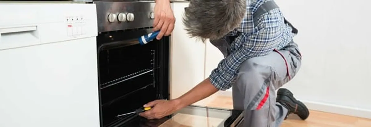 Oven repair technician inspecting and servicing an electric oven in Philadelphia, PA