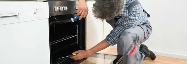 Oven repair technician inspecting and servicing an electric oven in Philadelphia, PA