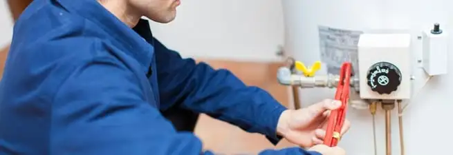 Water heater repair technician adjusting the temperature control and gas valve in Philadelphia, PA